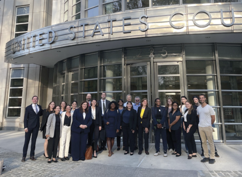 Counsel and advocates outside of the courthouse after oral argument. [cite: 128, 129]